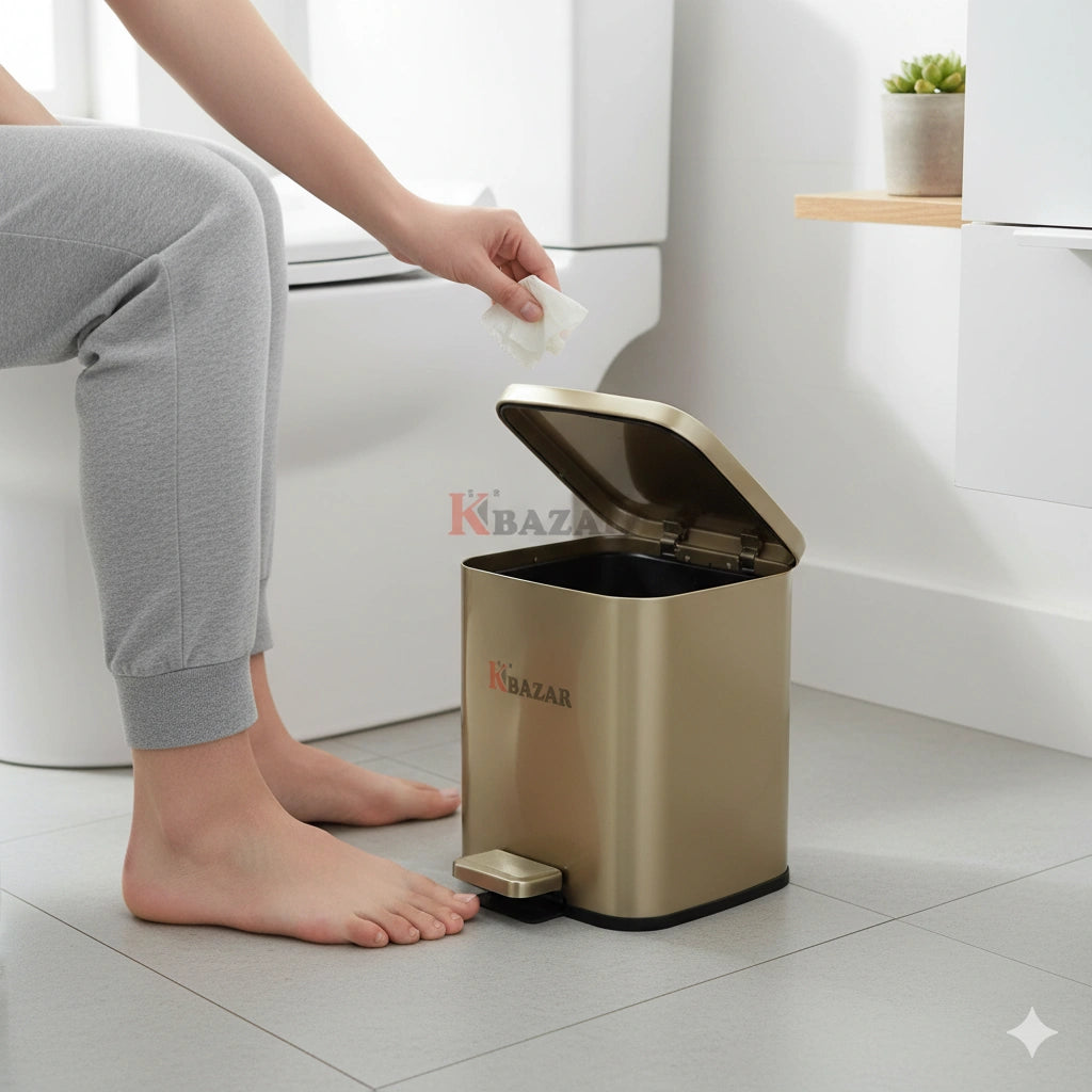 Person disposing of trash into a gold trash can in a bathroom setting.
