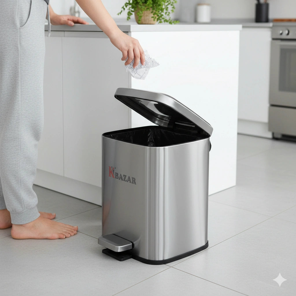Person disposing of trash into a stainless steel trash can with 'KRAZAR' branding in a kitchen setting.