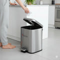 Person disposing of trash into a stainless steel trash can with 'KRAZAR' branding in a kitchen setting.