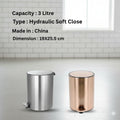 Two trash bins, one silver and one rose gold, on a light gray surface with a tiled wall background.
