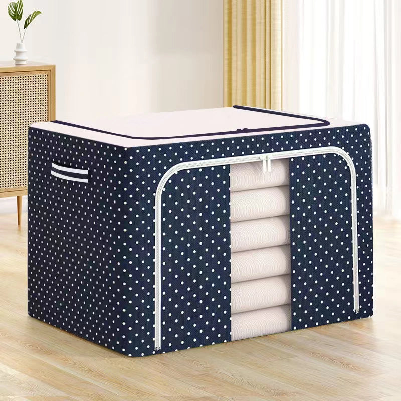 Navy blue storage cube with white polka dots containing folded white clothes on a wooden floor.