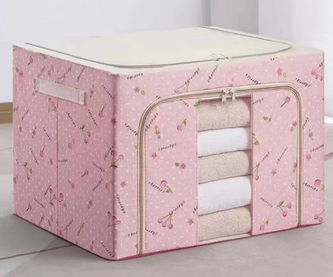 Pink storage cube with floral pattern containing folded clothes on a light background