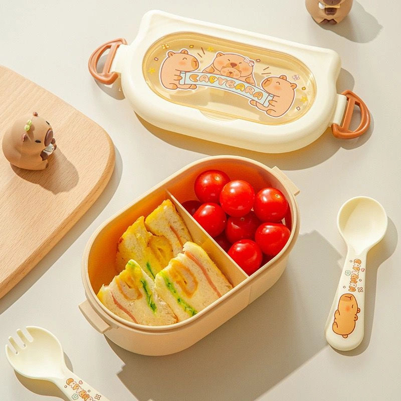 Children's bento box with cartoon design, filled with sandwiches and tomatoes, on a light surface.
