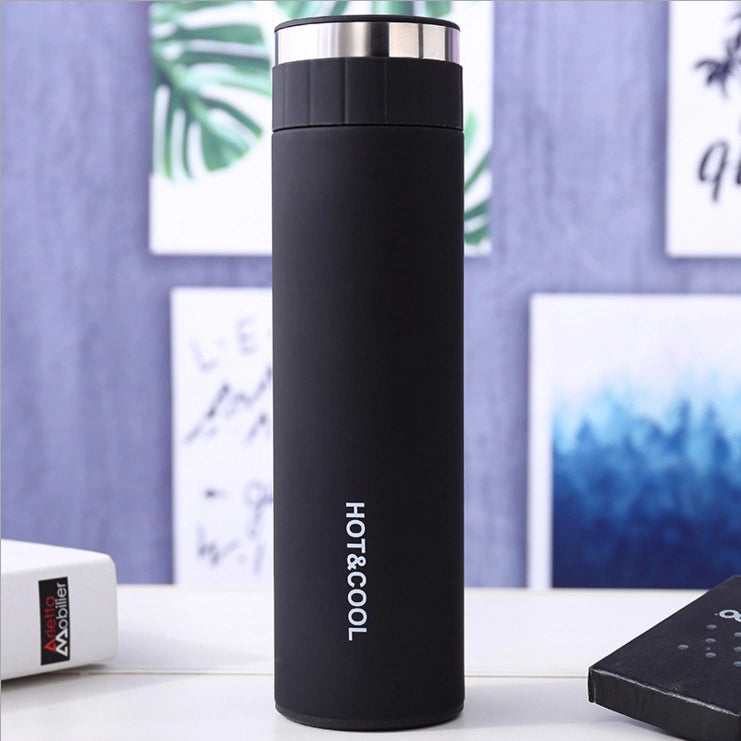 Black thermos bottle with 'HOT & COOL' text on a blurred indoor background