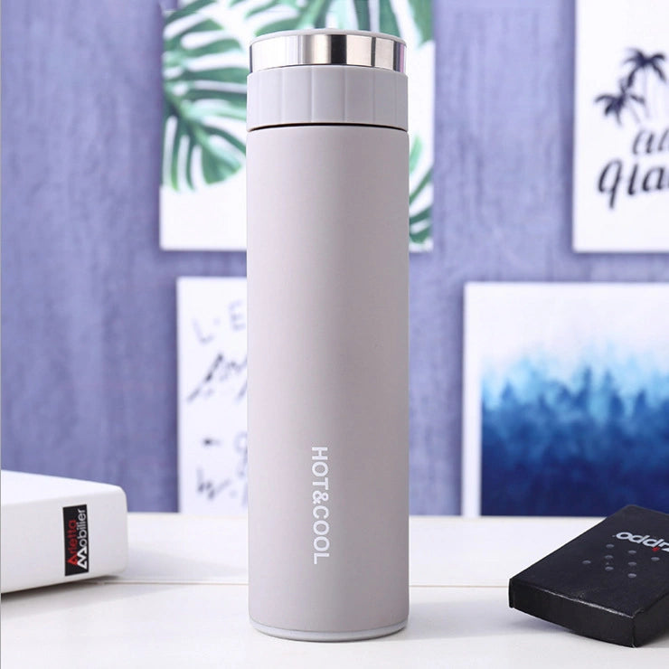 White thermos bottle with 'HOT & COOL' text on a blurred nature background