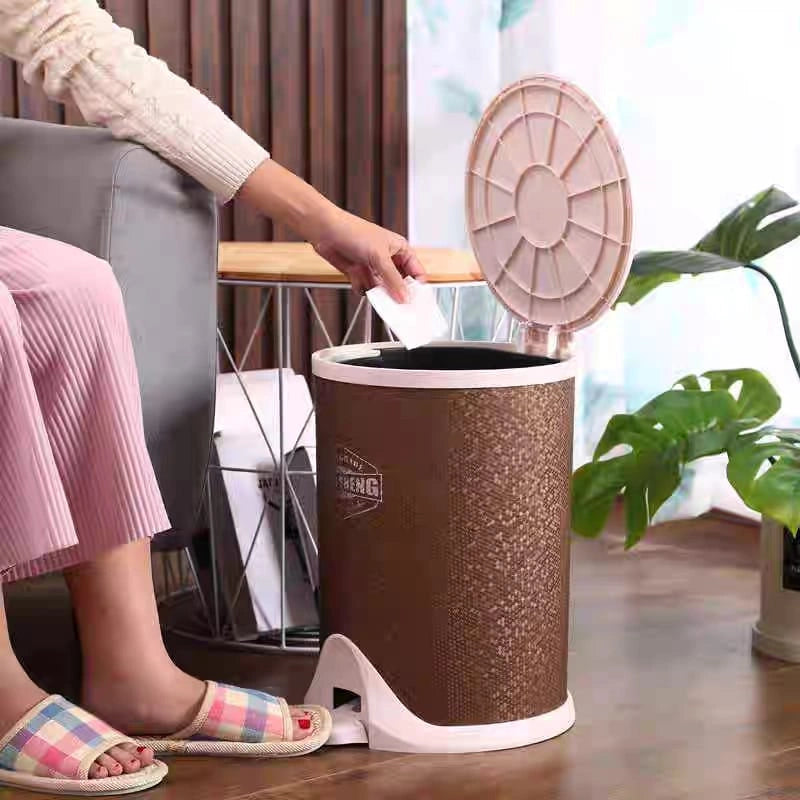 Person using a brown trash bin with a lid in a home setting
